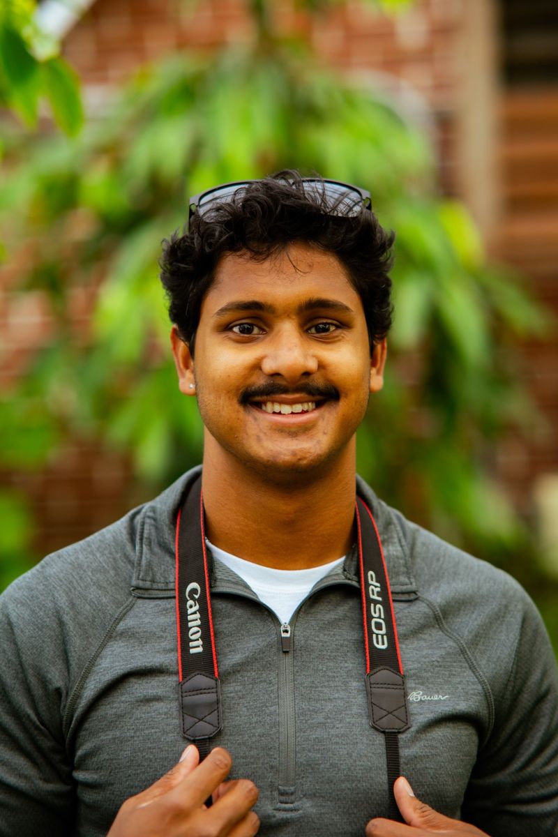Indy Larsen, photographer, smiling with a Canon camera strap around the neck