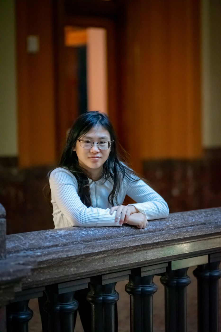 Senior portrait of a young woman leaning on a stone railing