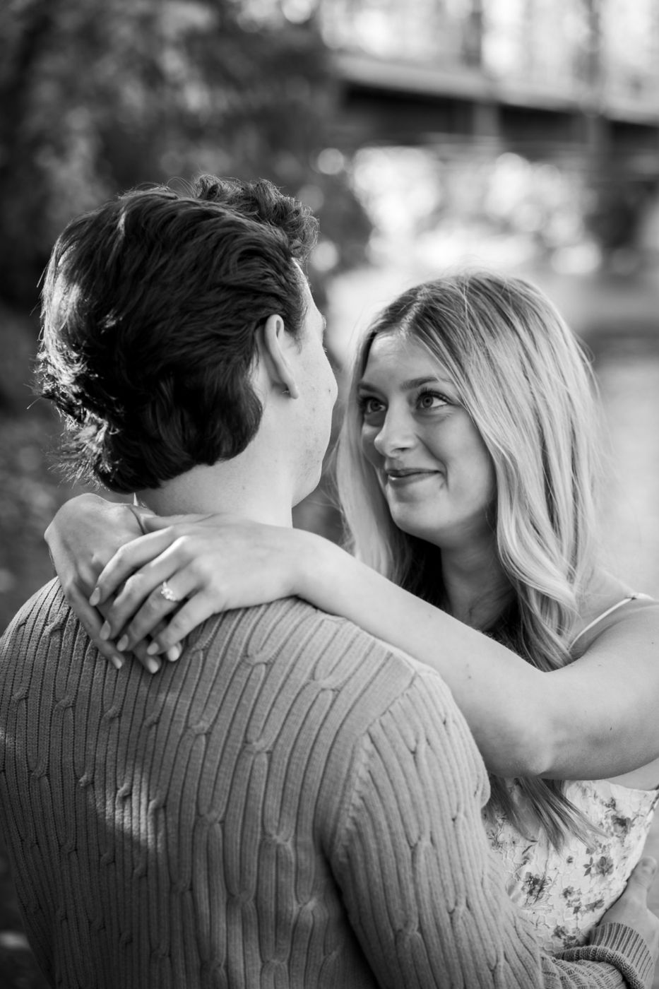 Black-and-white embrace, woman smiling up at her fiancé